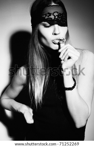 woman with black lace over eyes and ring in her mouth, bw studio shot,  grain added