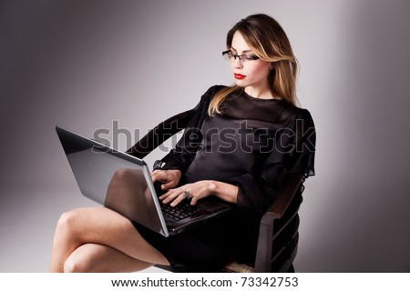 woman in elegant black dress with her laptop, studio shot