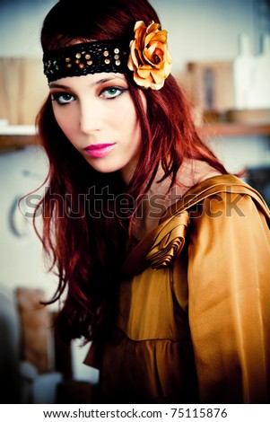 red hair woman in golden dress and headband with golden rose, indoor shot
