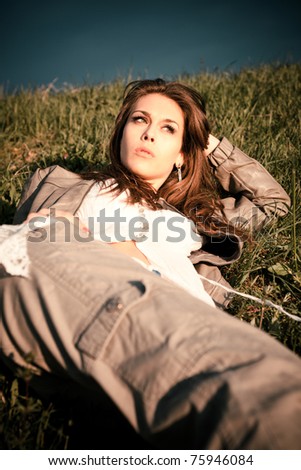 young woman lie in green grass on meadow, summer day sunset