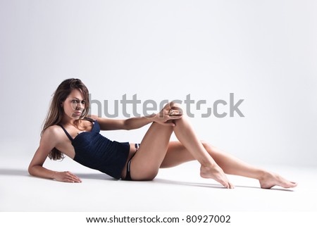 attractive tanned brunette in blue underwear lie on floor, full body shot, small amount of grain added, studio shot