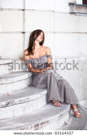 young woman in summer dress sit on stairs, waiting for someone, outdoor shot