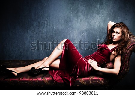 sensual elegant young woman in red dress on recamier indoor shot