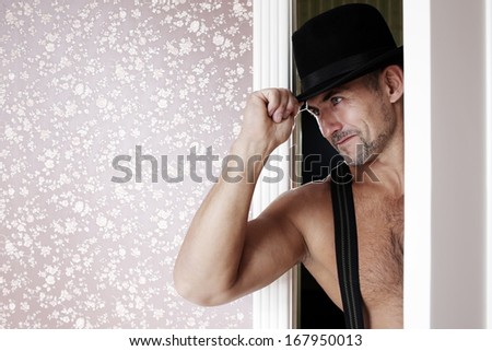 man in a hat and shirtless enters the room