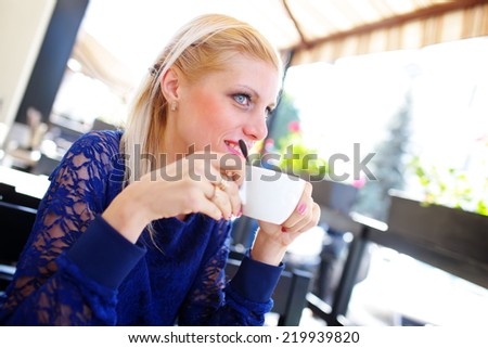 girl with straw-colored hair sitting over a cup of coffee in a good mood