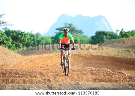 Man are riding mountain bikes uphill in a desert landscape.
