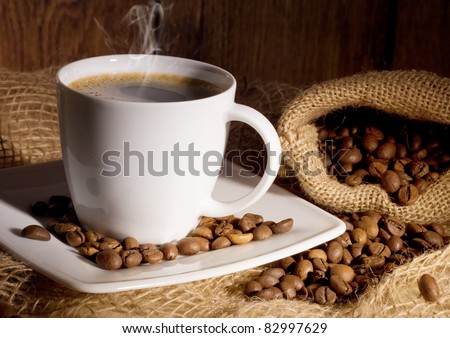 cup of coffee and coffee beans in a burlap bag