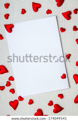 Bunch of hearts of various sizes scattered around an empty postcard