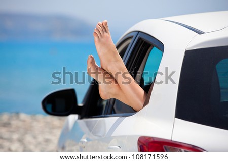 Women\'s legs sticking out the car window . The concept of relaxation and travel