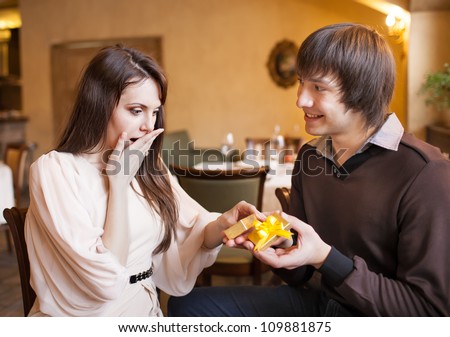 Attractive young couple with a gift in hands at restaurant