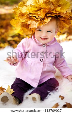 little cute girl in a wreath from autumn yellow leaves
