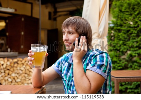Man with a cell phone drinks beer in a cafe
