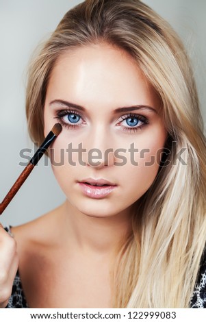 Beautiful woman with makeup brush near her face