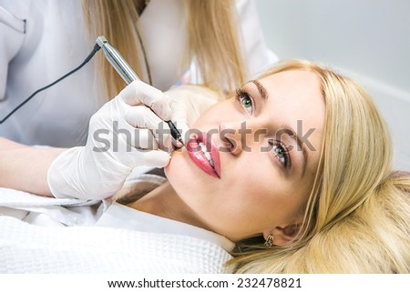 Cosmetologist applying permanent make-up on lips