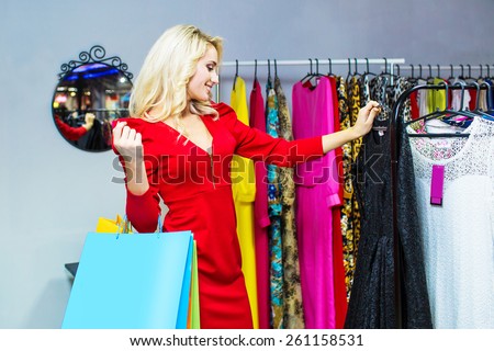 Woman choosing dress to wear in the shop. Shopping bags
