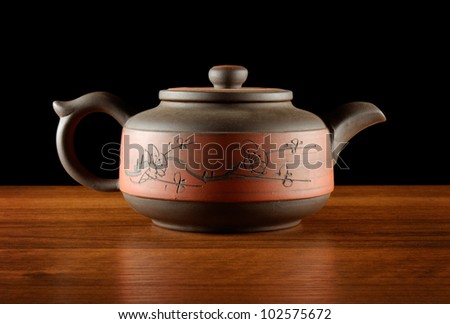 stylish kettle of red and brown clay standing on wooden desk, sideview