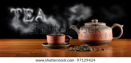 heap of tea, kettle and cup with hot tea and word 