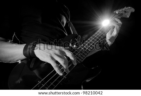 closeup of guitar player with bass guitar on stage
