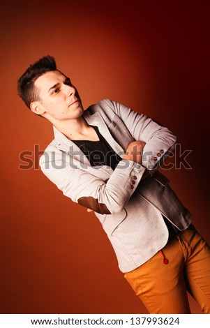 Fashion guy portrait with suit on orange background studio