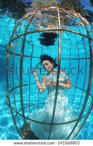 Fantasy bride underwater in a bird cage