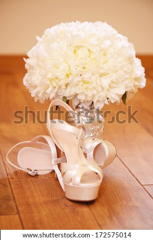 Elegant wedding shoes with beautiful bouquet on the floor