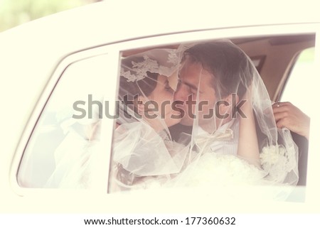Bride and groom kissing in a retro car