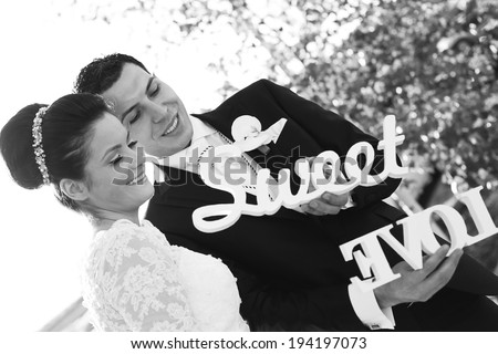 Black and white bride and groom having fun and posing with Sweet Love letters in sunlight