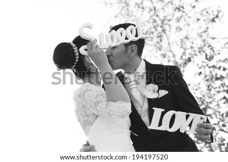 Black and white bride and groom having fun and posing with Sweet Love letters in sunlight