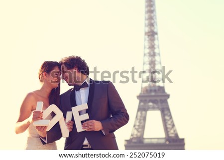 Bride and groom holding LOVE letters in their hand in Paris, France