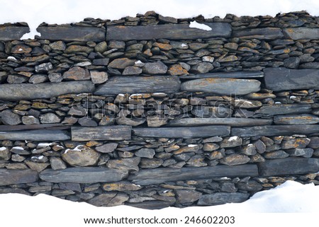 A traditional Georgian stone wall in the snow at the top and bottom.