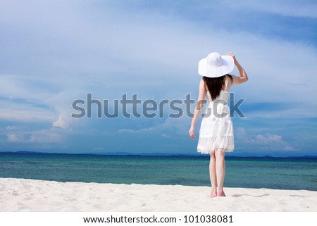 Young woman in a white dress walking on the beach