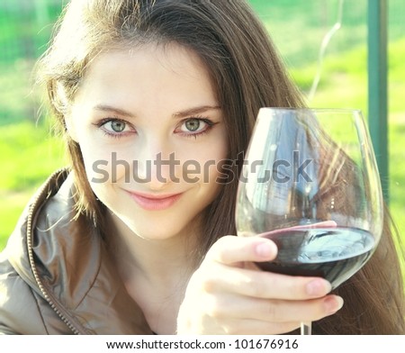 Red wine. Woman drinking red wine and looking with happy eyes. Closeup portrait of caucasian young beautiful model with long hair