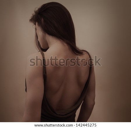 Beautiful woman with naked back in dress posing on dark background