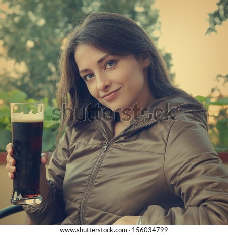 Smiling happy woman drinking dark beer on terrace cafe. Closeup vintage portrait