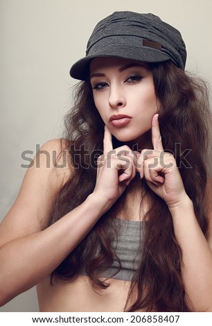 Hip-hop girl in hat posing and showing kissing sign holding fingers near lips