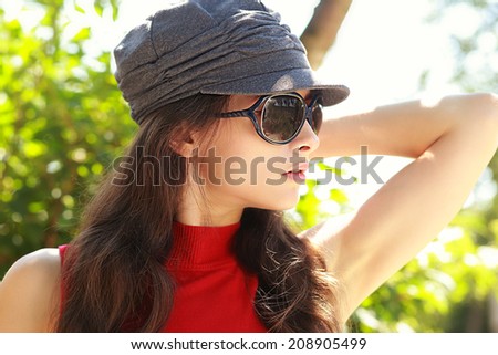 Sexy female model in sun glasses posing outdoors summer background. Closeup portrait