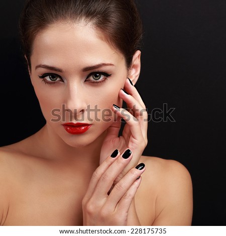 Beautiful makeup model looking with short black finger nails and red lipstick on black background