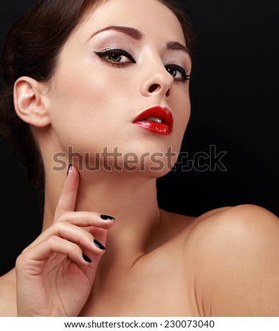 Beautiful female model with black eyeliner on eyes and red lipstick on black background. Closeup portrait