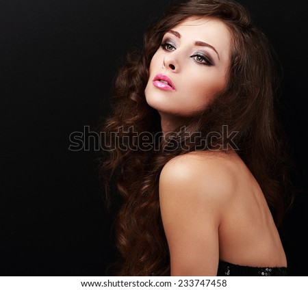 Beautiful makeup female model looking with curly hairstyle on black background with empty copy space
