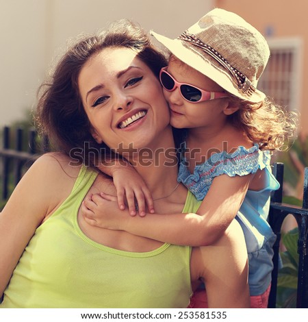 Happy kid girl embracing her smiling mother summer outdoors. Closeup vintage portrait