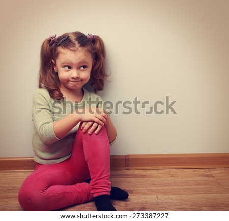 Thinking humor girl sitting on the floor in fashion clothes. Vintage closeup portrait with empty copy space