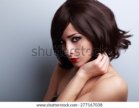 Sexy bright makeup woman with short black hair style on blue background. Closeup portrait