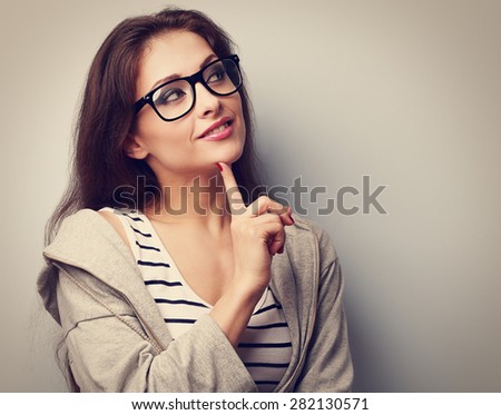 Beautiful young casual woman in glasses thinking with finger under face. Vintage closeup portrait