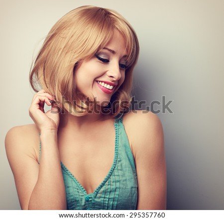 Pretty blond young woman with short hairstyle looking down. Natural smile. Color toned portrait