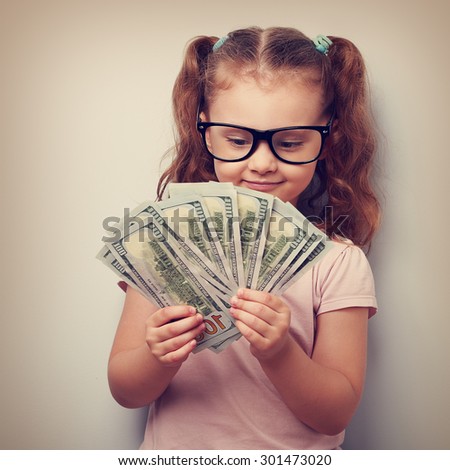 Happy kid girl in glasses looking on money and counting the profits. Vintage closeup portrait
