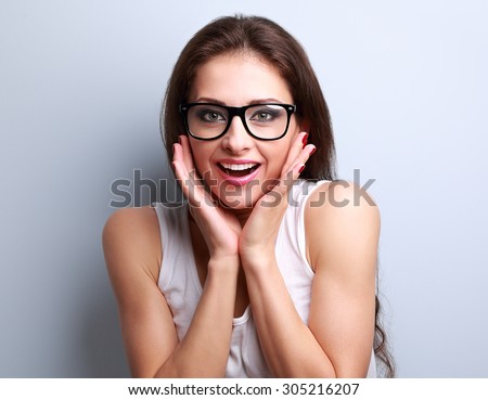 Surprised fun young woman in eye glasses with open mouth looking on blue background with empty copy space