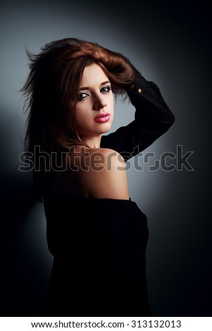 Sexy makeup woman in black shirt posing on dark shadows background