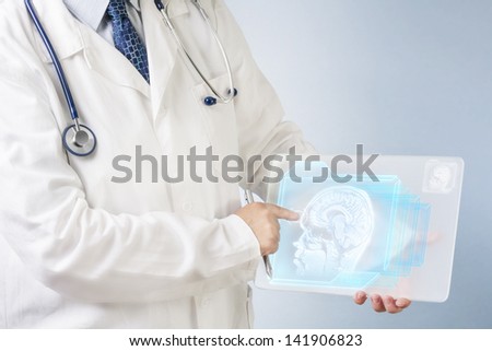 Physician showing futuristic transparent tablet head and brain scans.