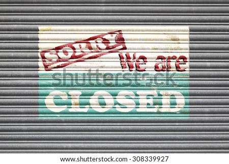 Metal shutter with sorry we are closed painted shop sign.