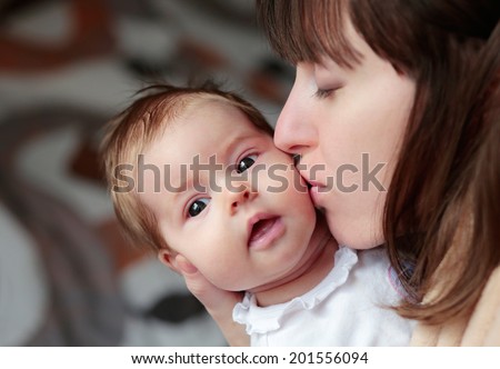 Young happy mother kissing cute newborn baby